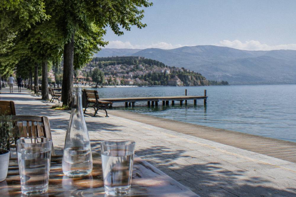 Bottled water and glasses on a cafe table beside the Ohrid lakeside promenade