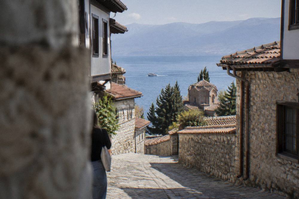 A small boat crossing open blue water on Lake Ohrid with mountains in the distance