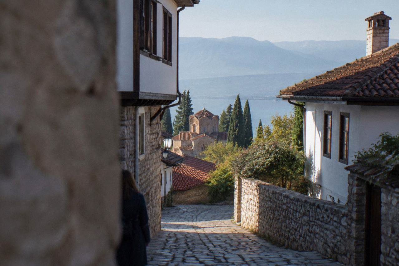 A stone lane in Ohrid's old town with whitewashed houses rising toward the fortress walls