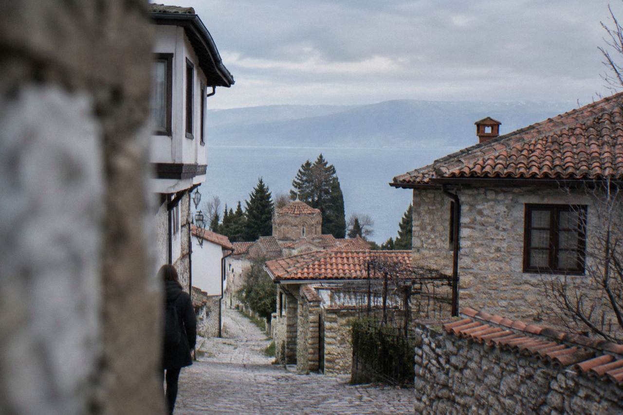 A lakeside street in Ohrid with stone houses descending toward the blue water of Lake Ohrid