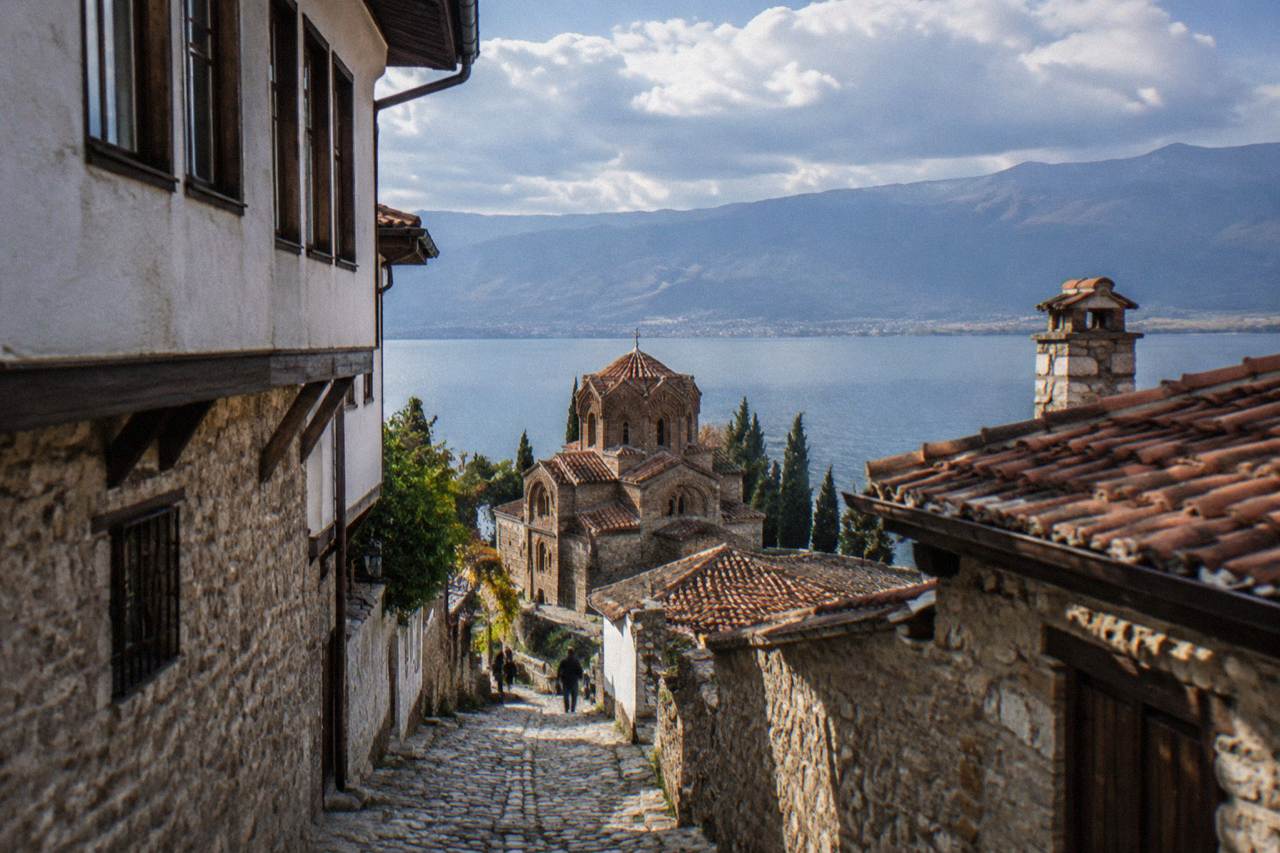 Stone church above the shoreline of Lake Ohrid with old-town rooftops behind it