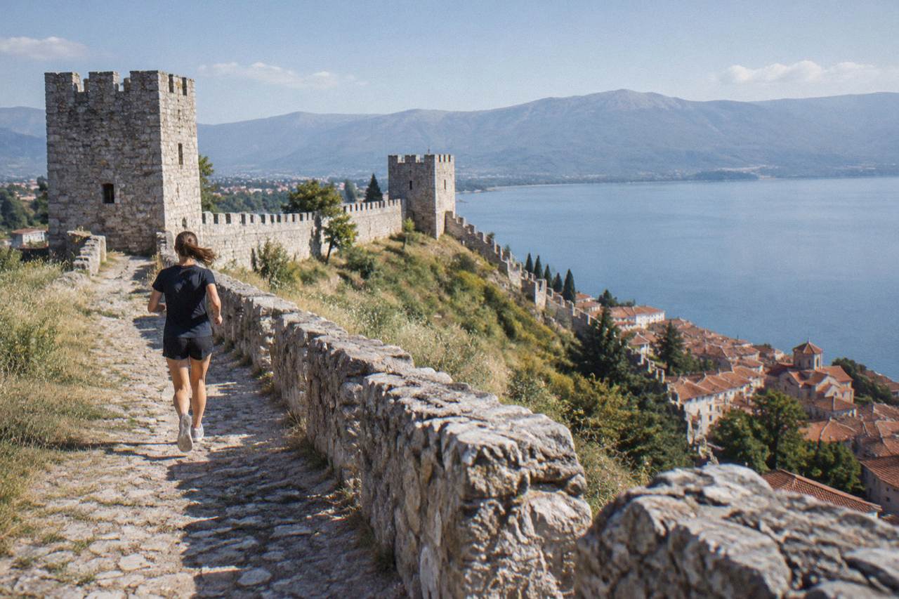 Stone fortress walls on a hill above the red roofs of Ohrid old town and Lake Ohrid