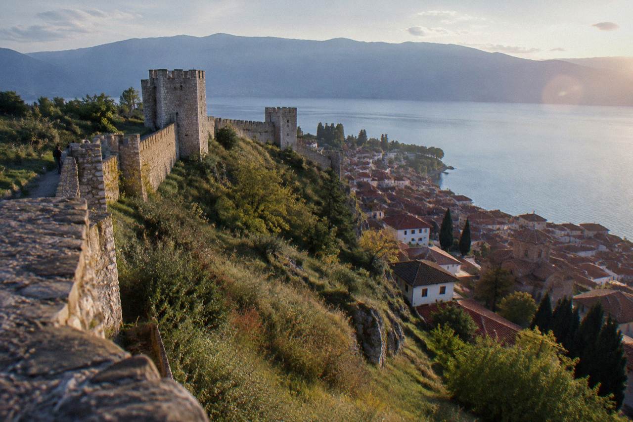 Stone walls of a hillside fortress above the red roofs of an old lakeside town