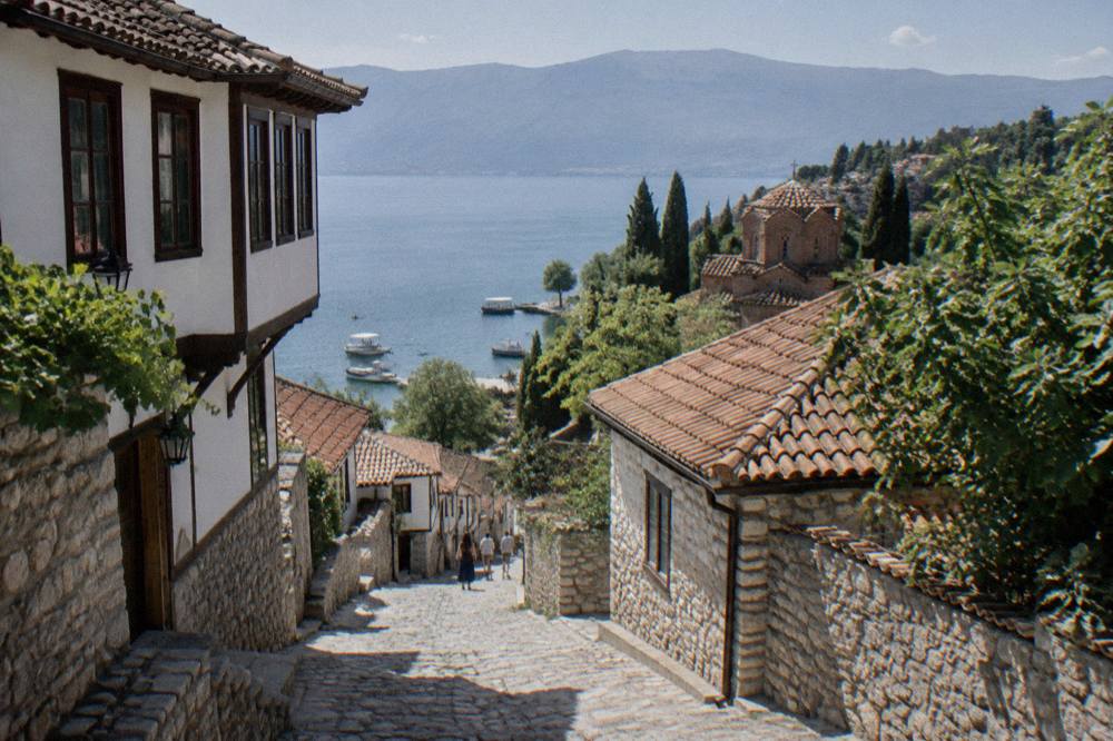 Boats moored along the lake shore below Ohrid's old town at midday