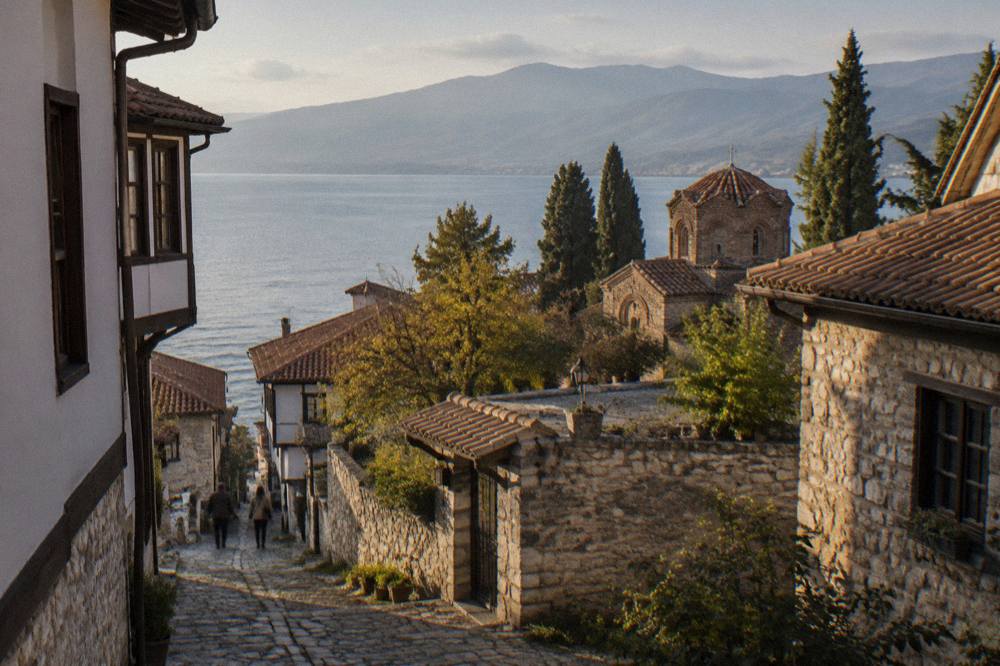 A stone monastery courtyard above the shore of a wide mountain lake