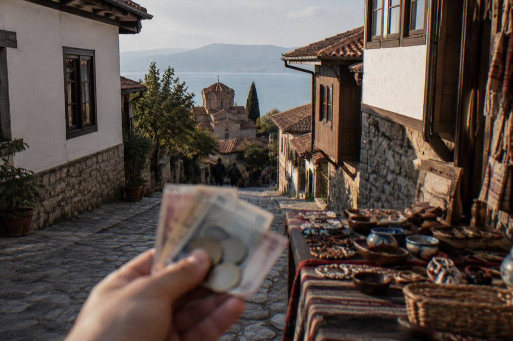 Denar banknotes and coins held in a hand above a market stall table