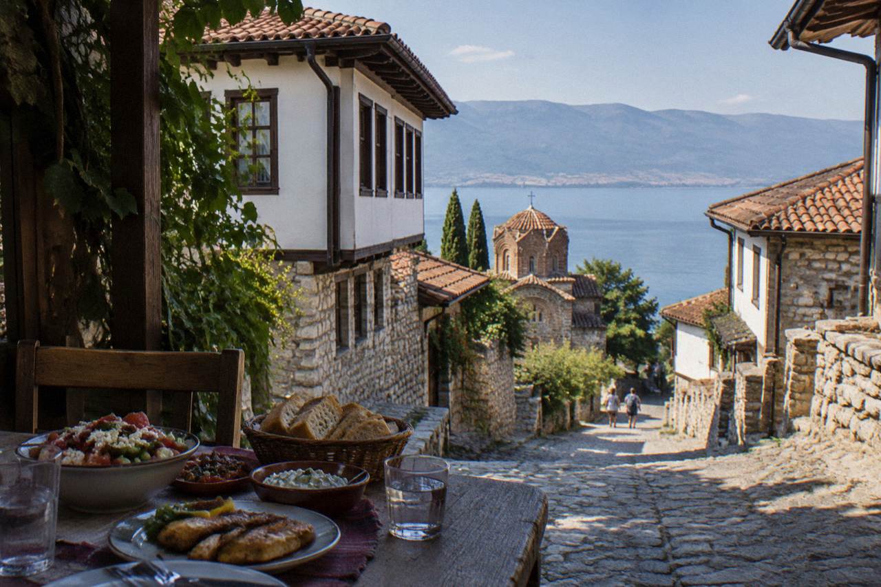 A rustic restaurant table beside Lake Ohrid with shared dishes and bread