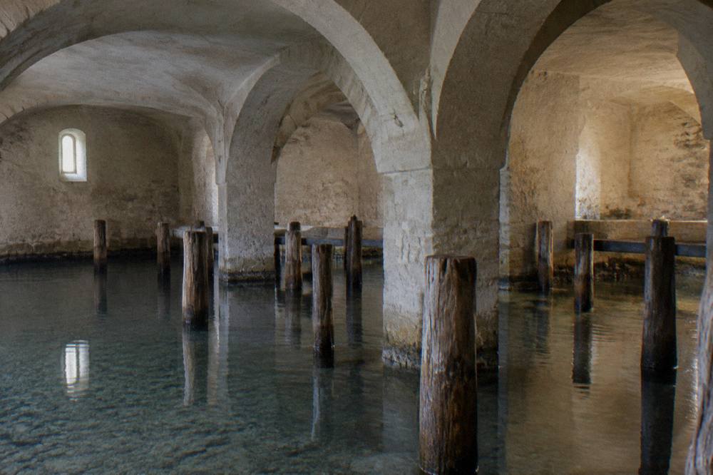 Wooden pilings of the Bay of Bones reconstructed lake settlement standing in clear shallow water near Peshtani