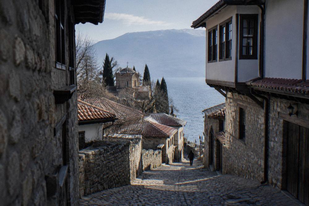 Clear water of Lake Ohrid along a pebble shore near Ohrid with hills behind