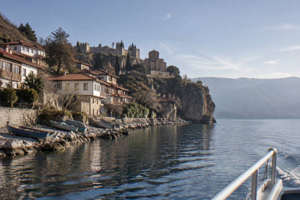 A panoramic boat cruising on Lake Ohrid past the cliffs and old town frontage near Kaneo