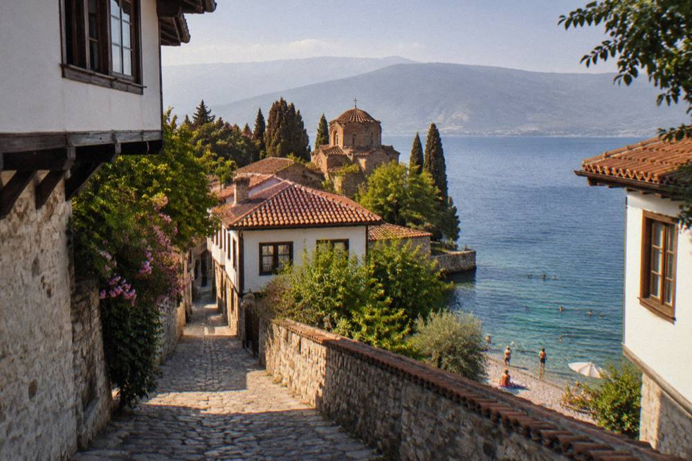 People swimming from a pebble beach into clear green water on Lake Ohrid in summer