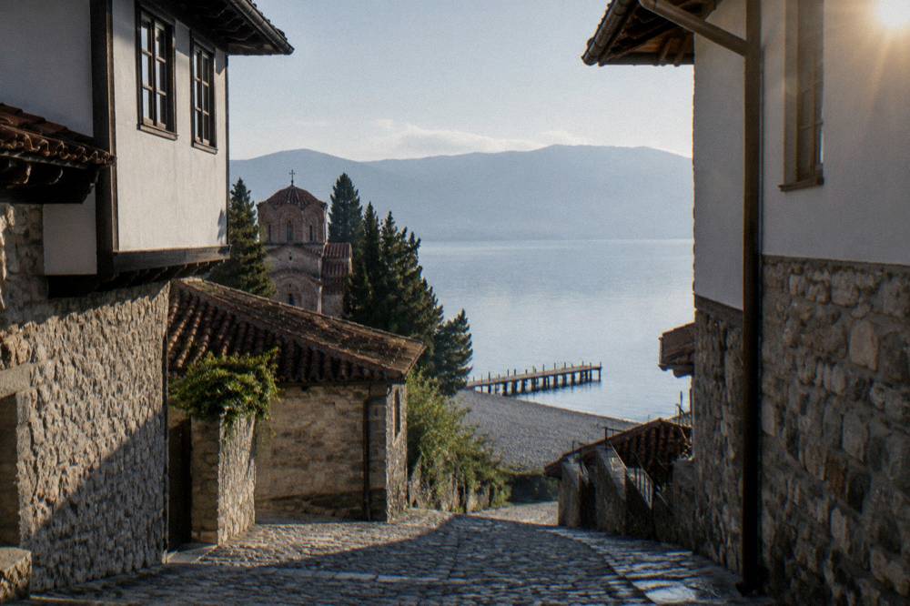An empty pebble beach on Lake Ohrid in calm morning light with a jetty reaching into the water