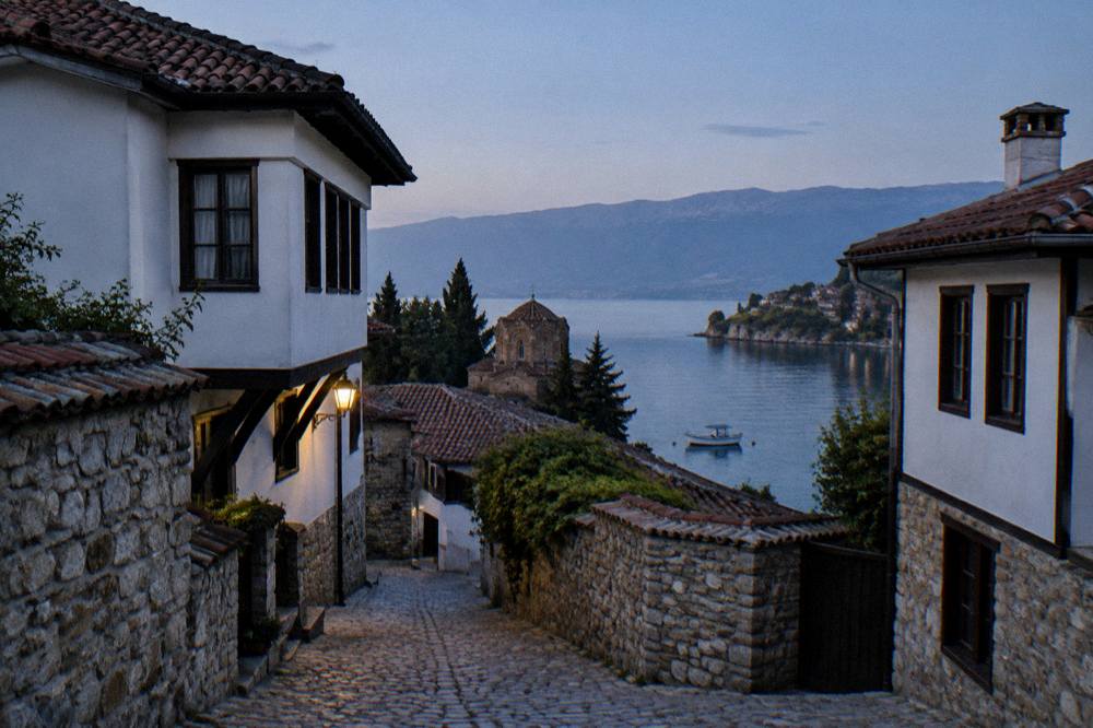 A small boat moored in a clear bay on Lake Ohrid with a village visible along the shore
