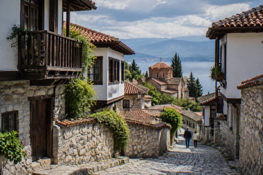 A narrow stone lane winding uphill between old houses with wooden balconies