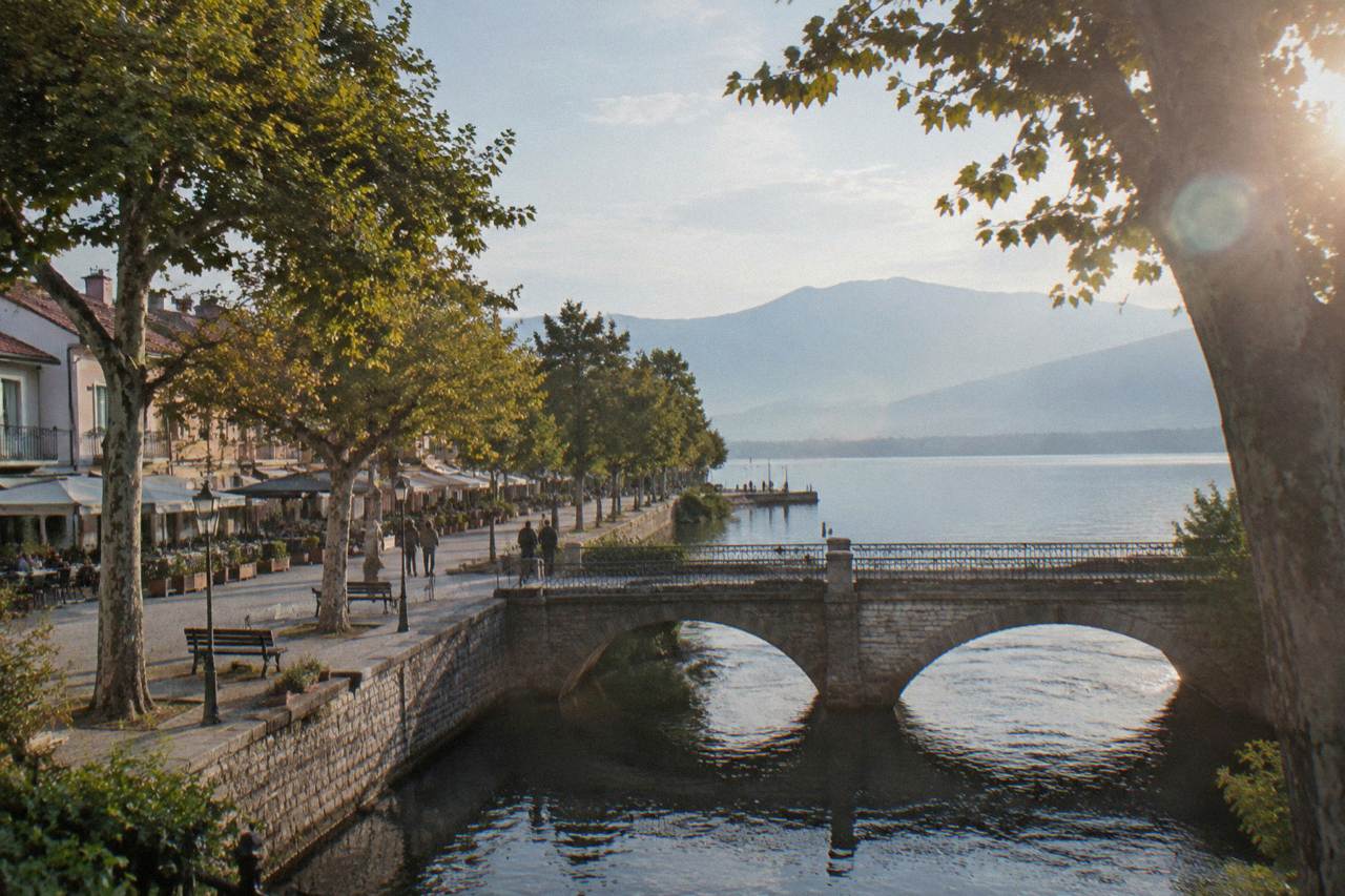 A stone bridge over a river running through a small lakeside town