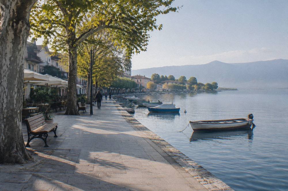 Flat waterfront promenade beside a calm lake with moored small boats