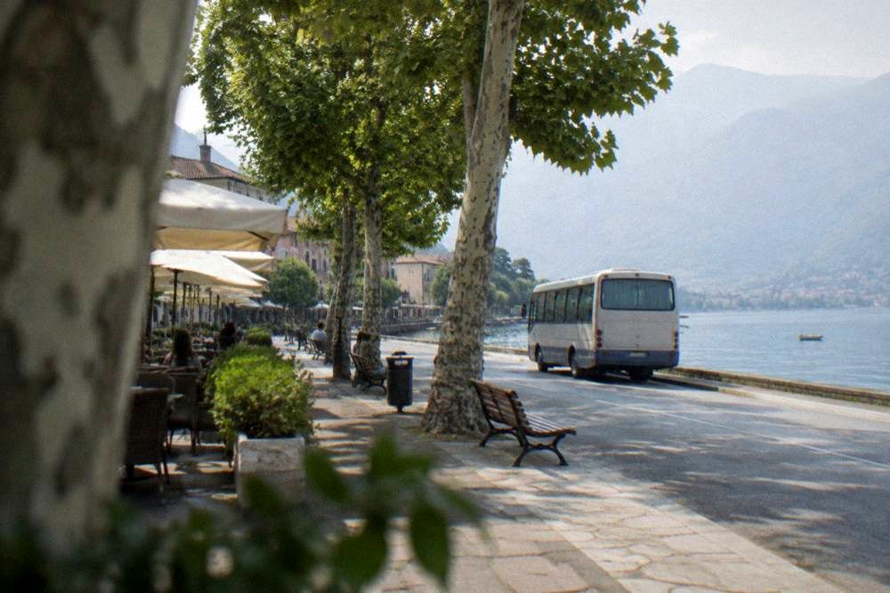 A small regional bus parked at a roadside stop near a lake
