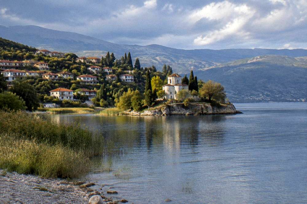 A village of houses among trees above a small bay on Lake Ohrid's eastern shore