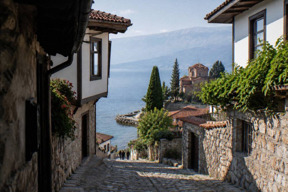 Clear water over pale pebbles at the edge of Lake Ohrid with a low stone jetty