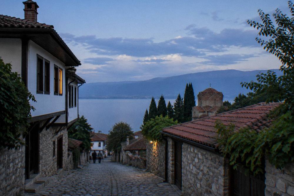 Wooded slopes above Lake Ohrid under a partly cloudy sky, seen from the water