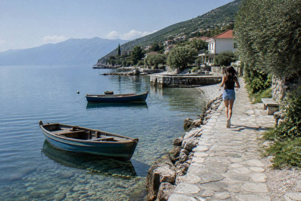 Small wooden boats moored in clear shallow water beside a stone quay