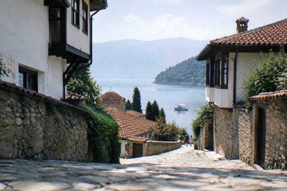 A small pleasure boat moored in a calm bay on Lake Ohrid with wooded hills behind