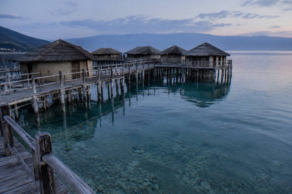 Turquoise shallow water over a pebble lakebed seen from a wooden jetty