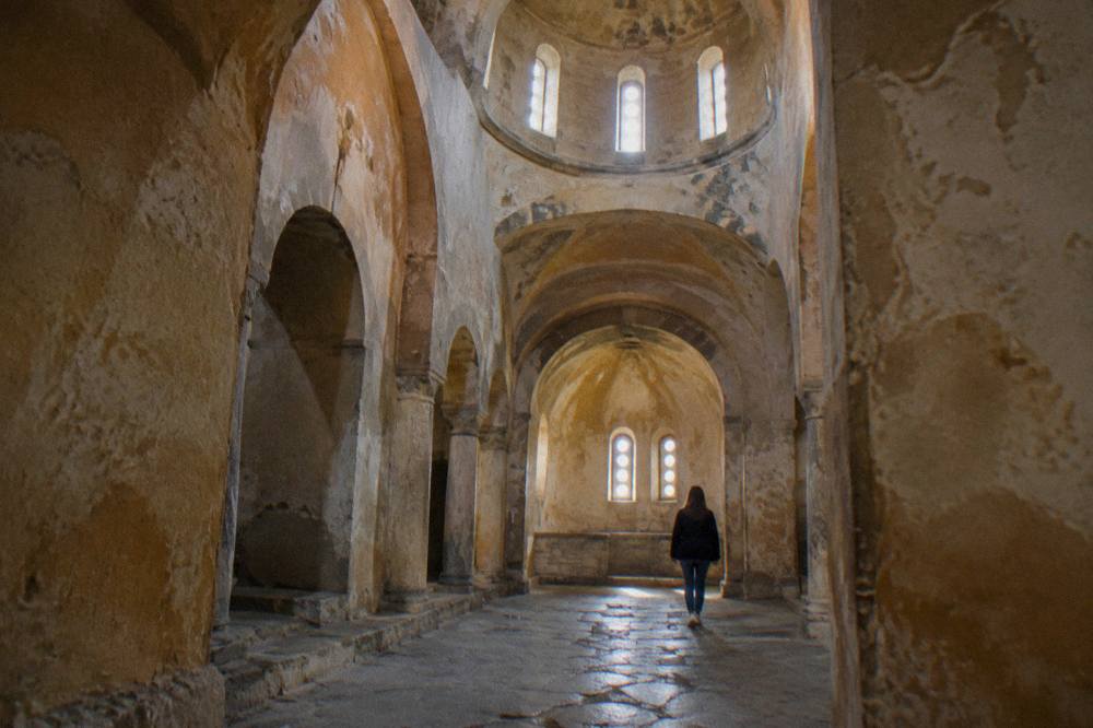 Stone arches and a small dome inside a Byzantine church in Ohrid in soft window light