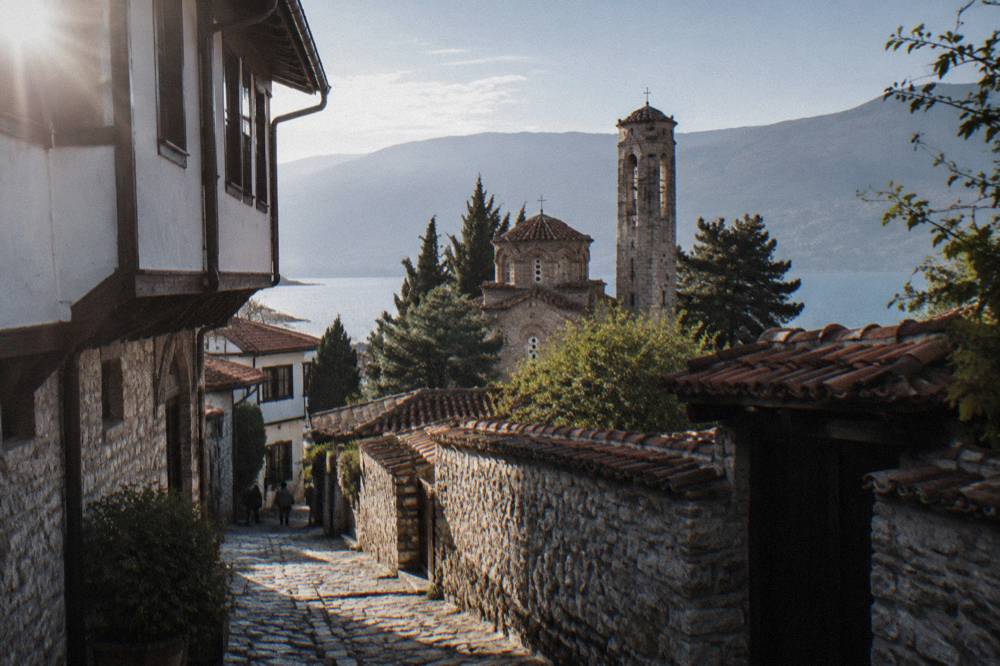 Exterior of a small stone church with a bell tower among trees in Ohrid
