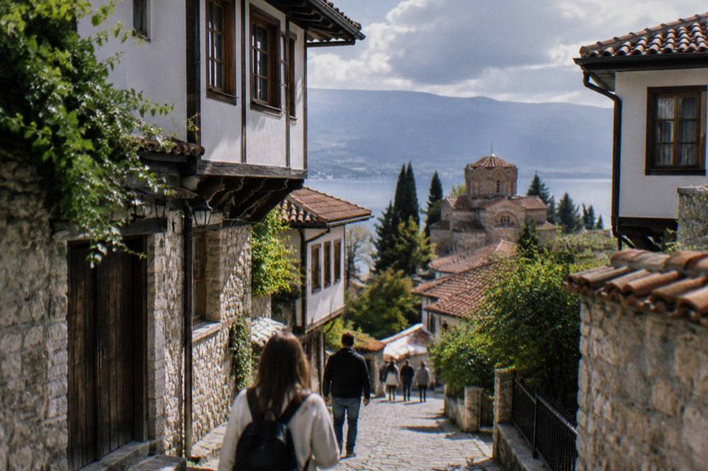 Visitors walking a cobbled street between stone houses in Ohrid old town