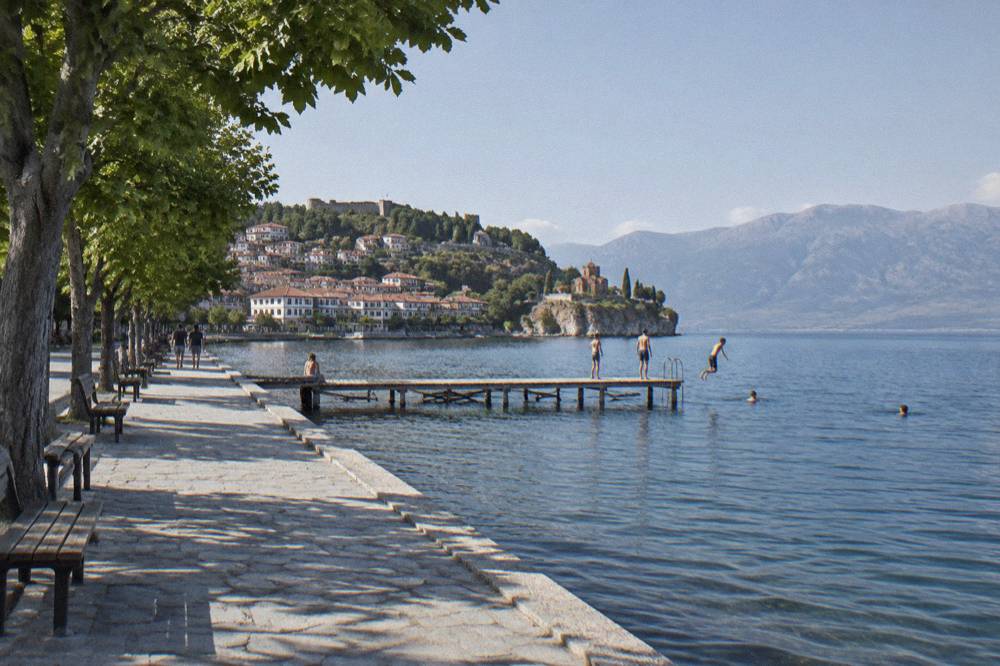 People swimming from a wooden jetty into deep blue lake water