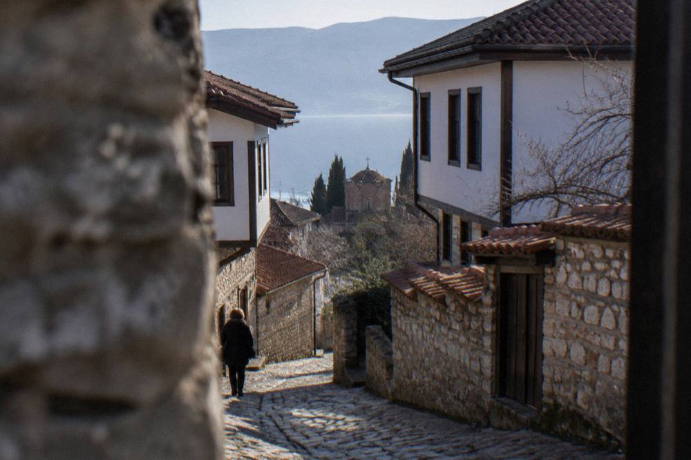 A narrow cobbled lane climbing between old stone houses in Ohrid