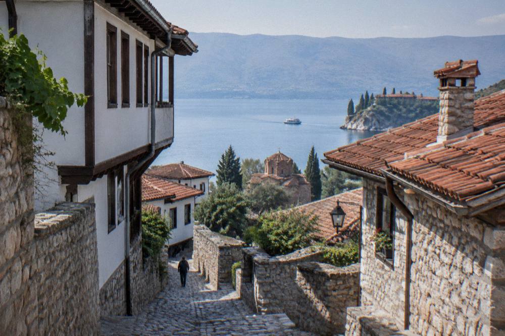 A small boat crossing the clear water of Lake Ohrid toward a monastery point