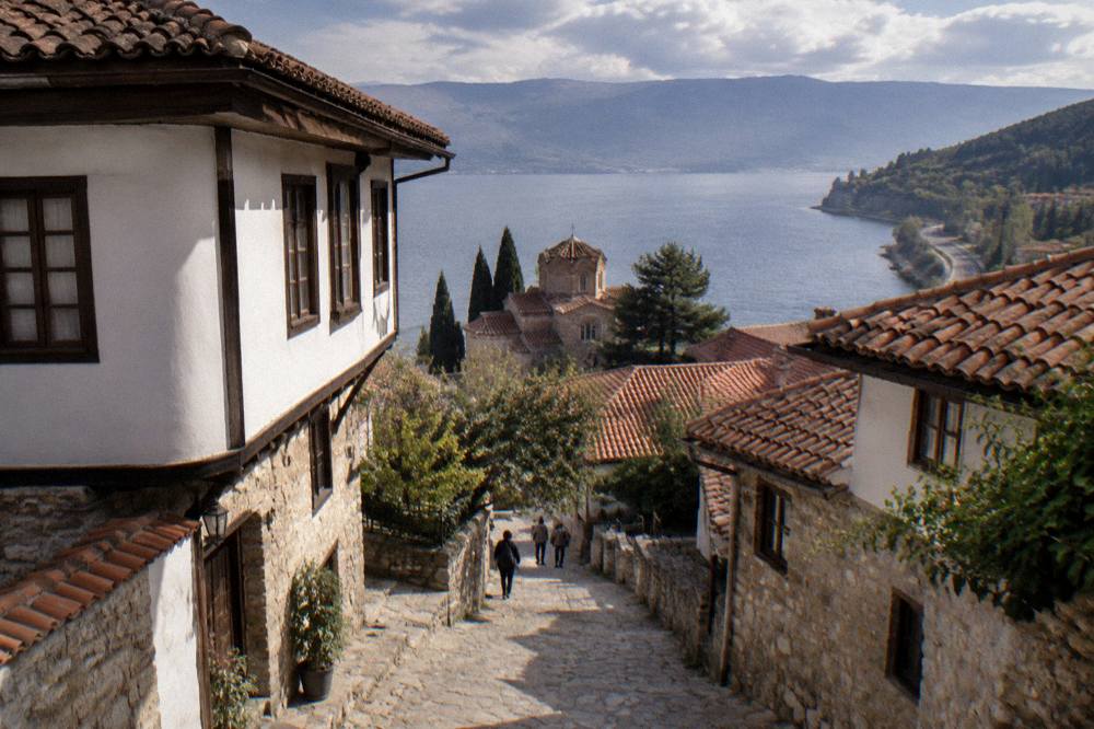 A road winding along the shore of Lake Ohrid toward forested hills