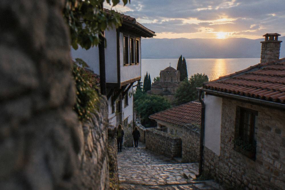 The sun setting over Lake Ohrid with the silhouette of a church dome above the water