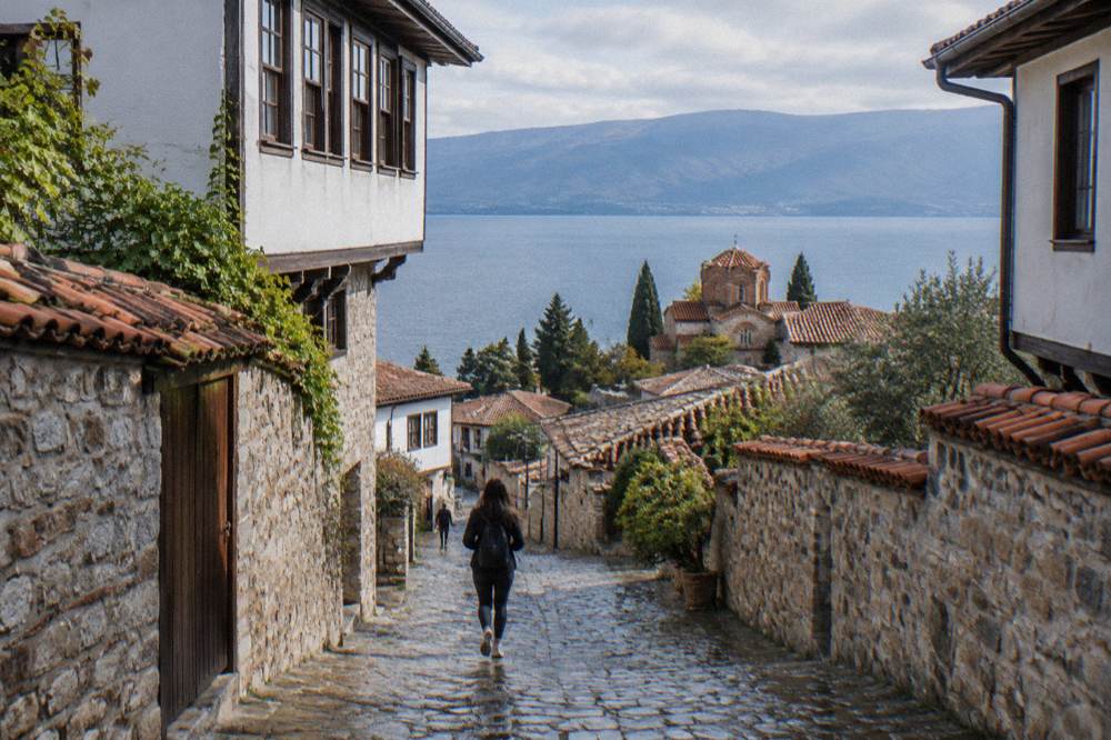 Panorama of terracotta roofs of an old town sloping down to a wide blue mountain lake