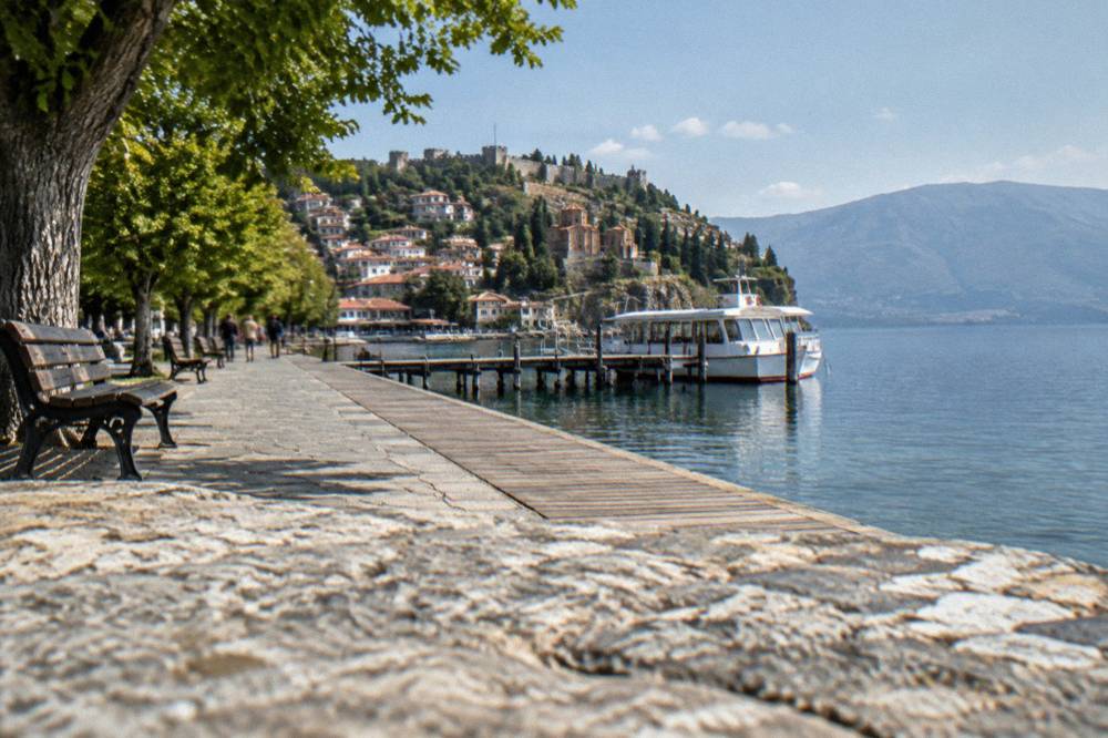 A white tourist boat moored at a wooden jetty on a blue lake