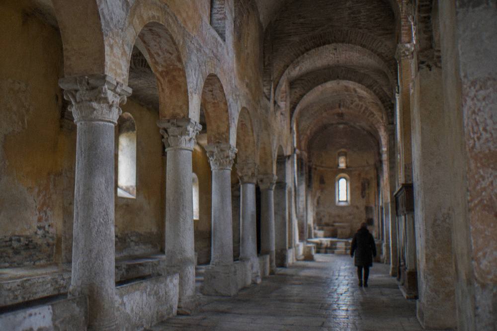 A stone arcade with pale columns inside a Byzantine church in Ohrid