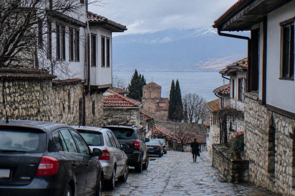Row of parked cars and stone houses on a street at the edge of Ohrid old town