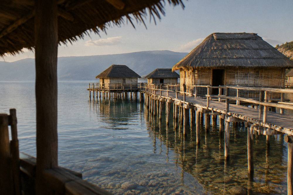 A reconstructed prehistoric pile dwelling standing on stilts over a lake bay