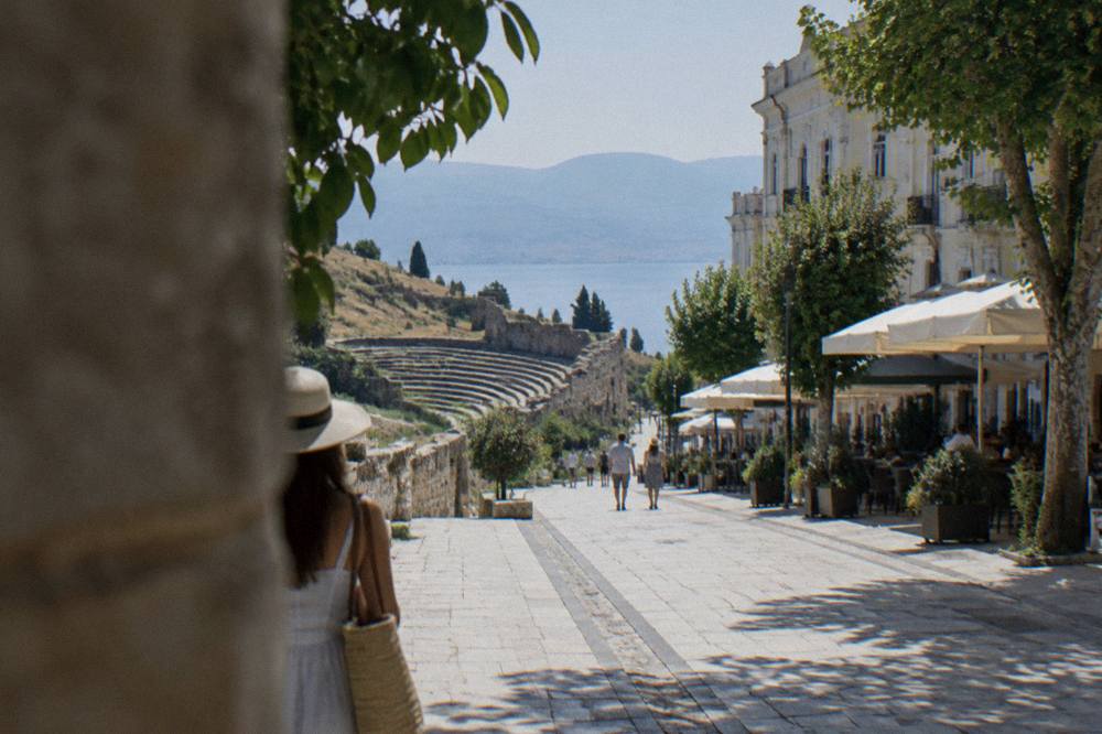 An ancient stone theatre on a hillside above a lake town with rows of seating