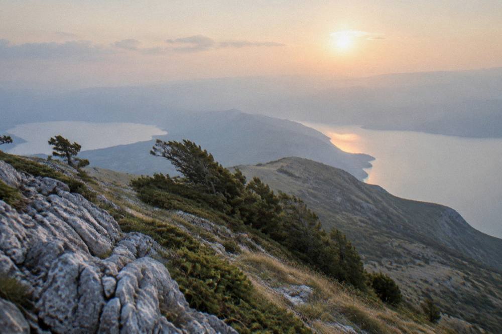 Sunset light over a mountain ridge with two lakes glowing in the valleys on either side