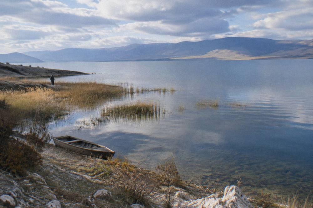 A view from a high ridge over a wide blue lake stretching to distant mountains
