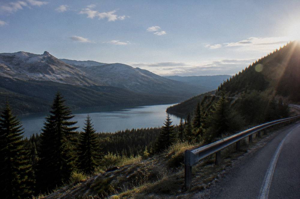 An empty road winding along a hillside above a valley