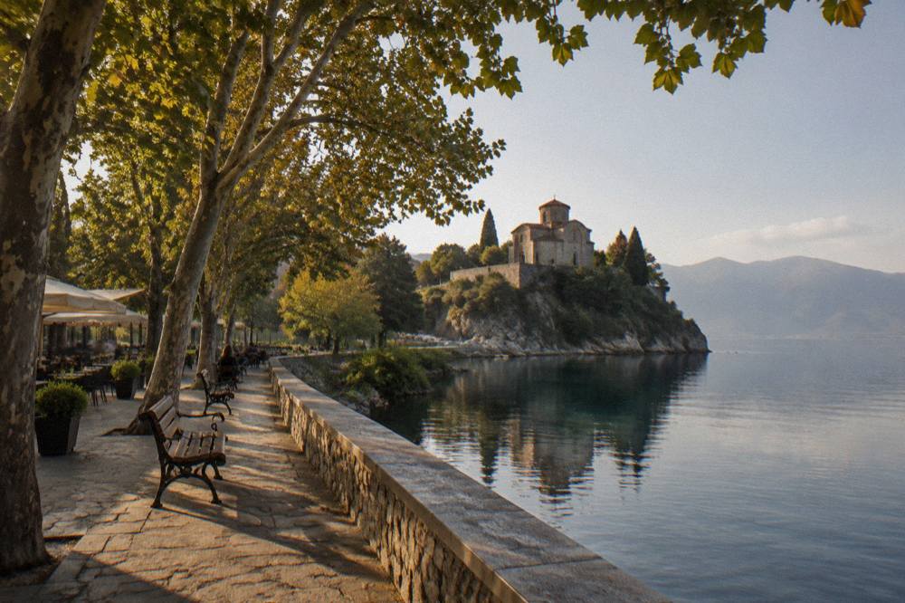 A stone church on a headland above the still water of a mountain lake