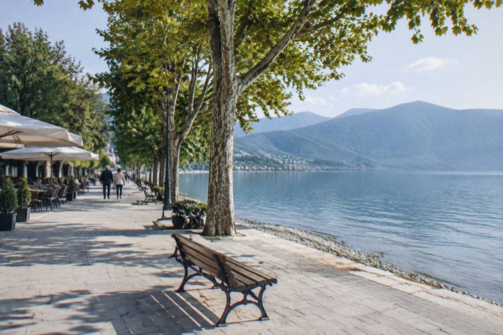A quiet border-point road between green hills at the southern end of a lake