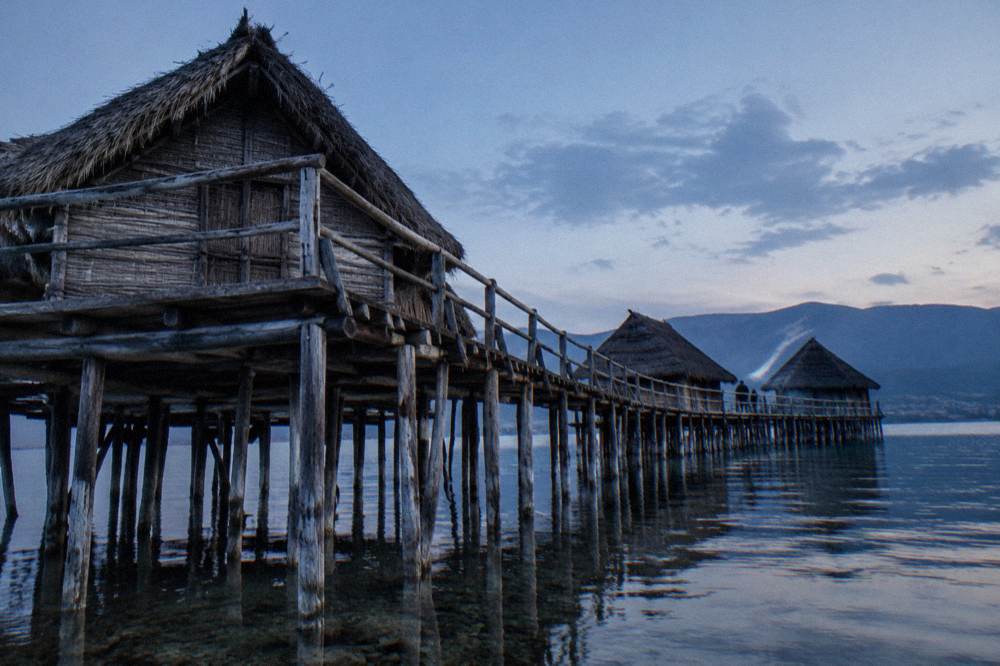 A reconstructed pile-dwelling museum standing on stilts above a lake bay