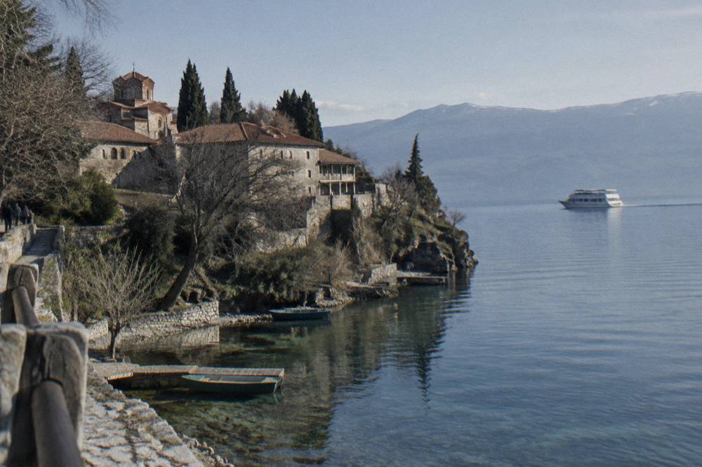A white cruise boat travelling across open water with mountains along the far shore
