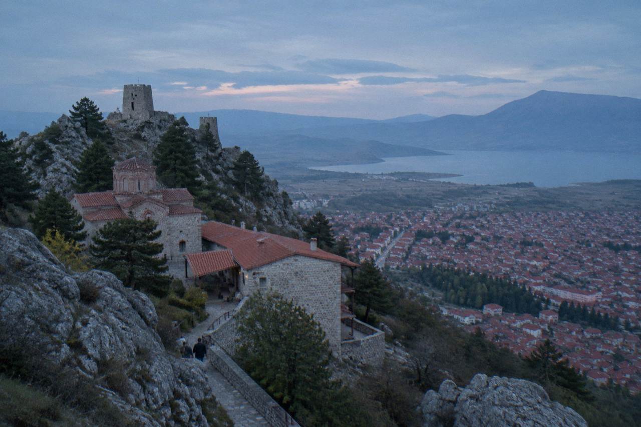 Stone towers on a rocky hill above a red-roofed town under a wide sky