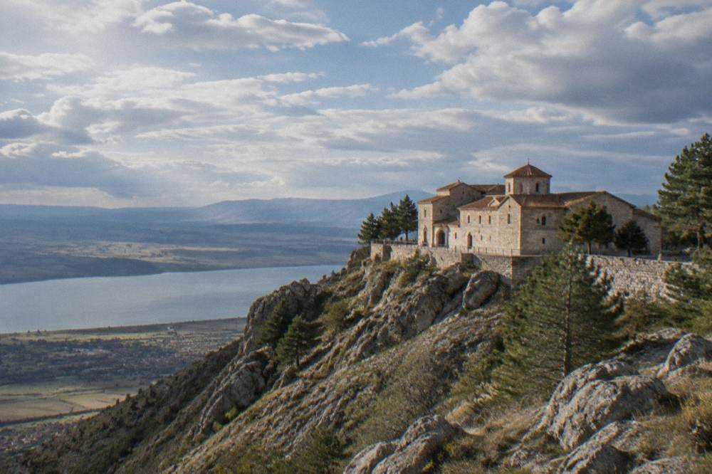 A monastery building standing alone on a high ridge above plains